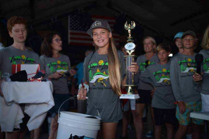 Girl holding trophy next to friends  