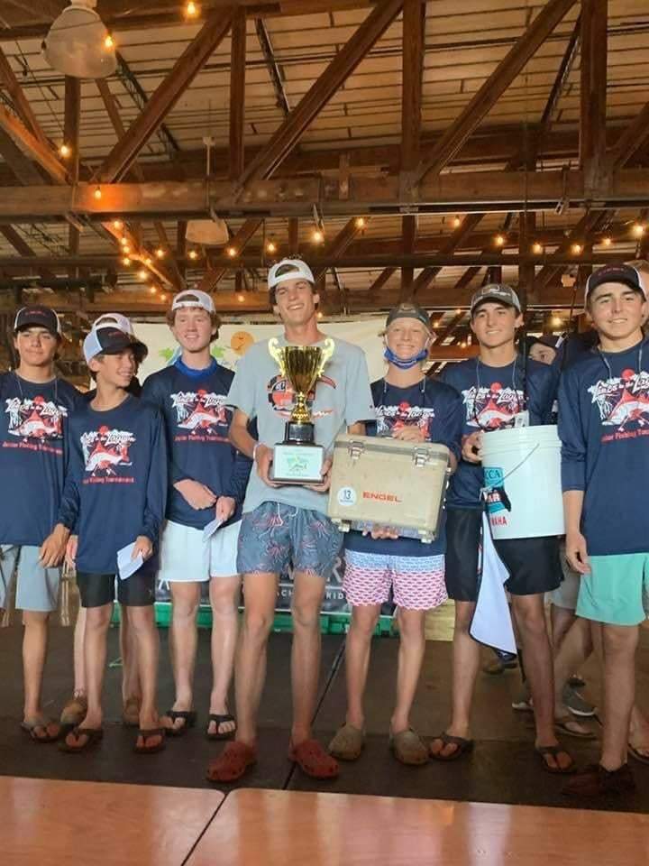 Boy holding a trophy on the stage with other boys 
