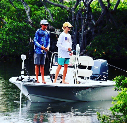 Two young boys fishing off a motor boat